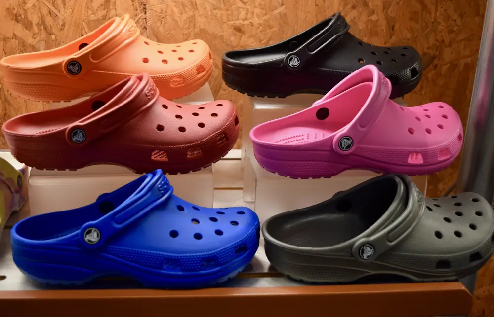 6 Crocs on a store shelf in different colors in Blue, Black, Orange, Pink and Red