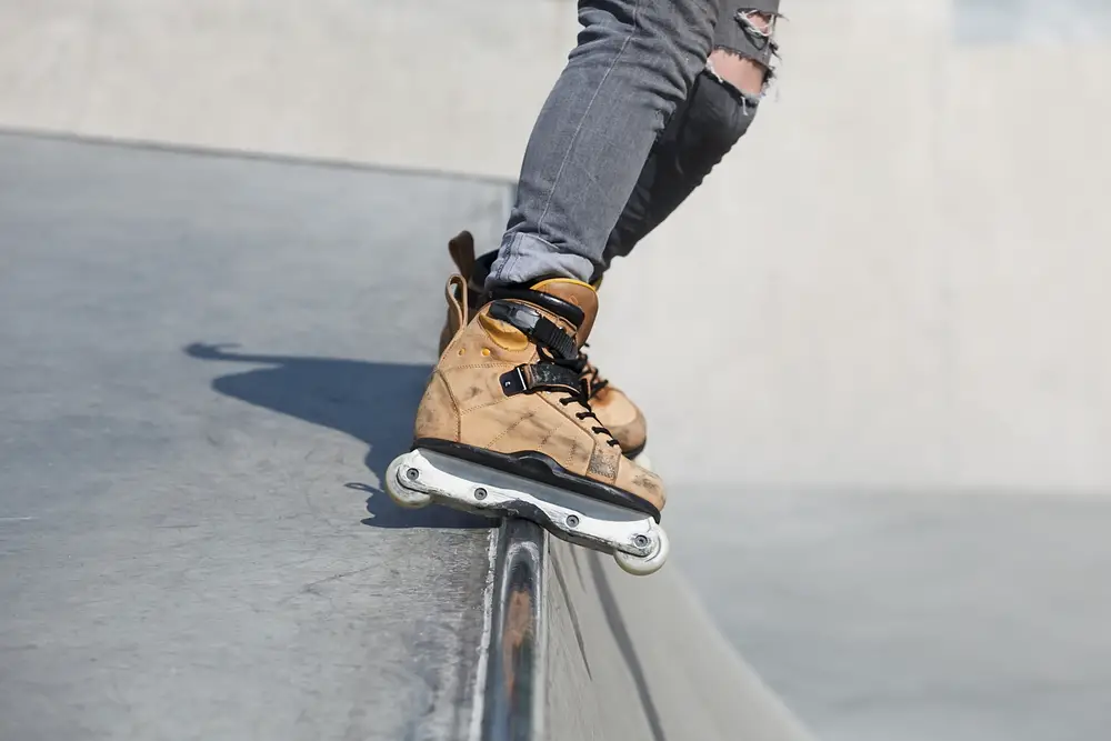 Feet of rollerblader wearing aggressive inline skates grinding on concrete ramp