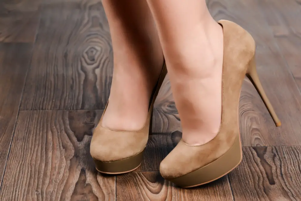 Girl in beige suede almond toe pumps high-heeled shoes on the wooden floor