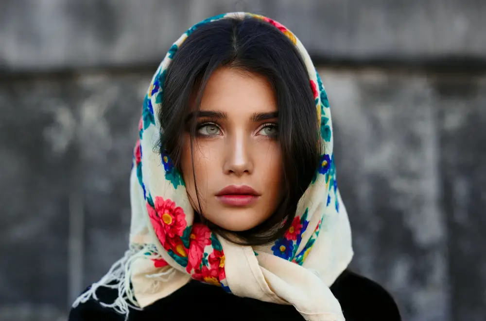 fashionable young woman with perfect make up posing in colorful shawl on her head