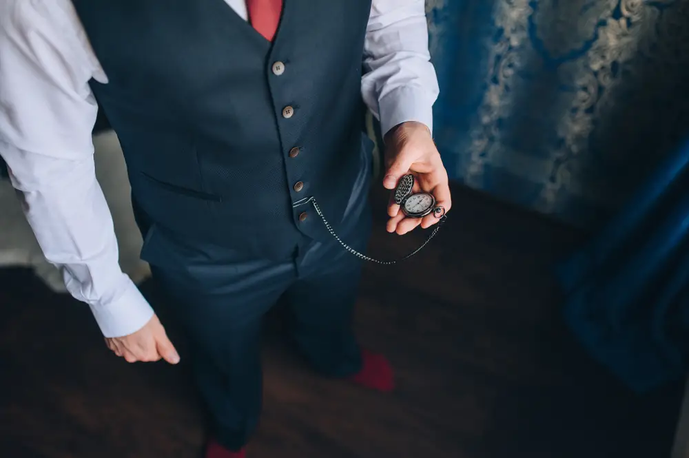 man in a suit holds in his hands a vintage pocket watch