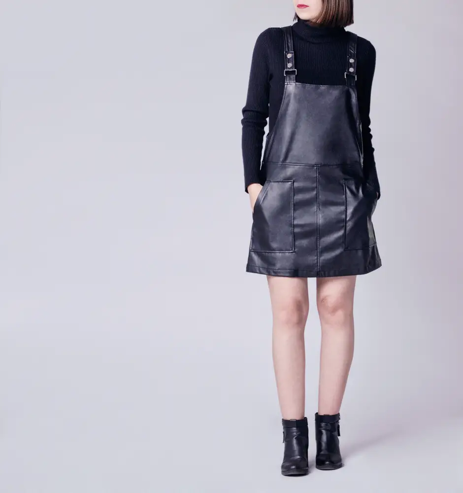 woman wearing stylish outfit with black faux leather pinafore dungaree mini dress