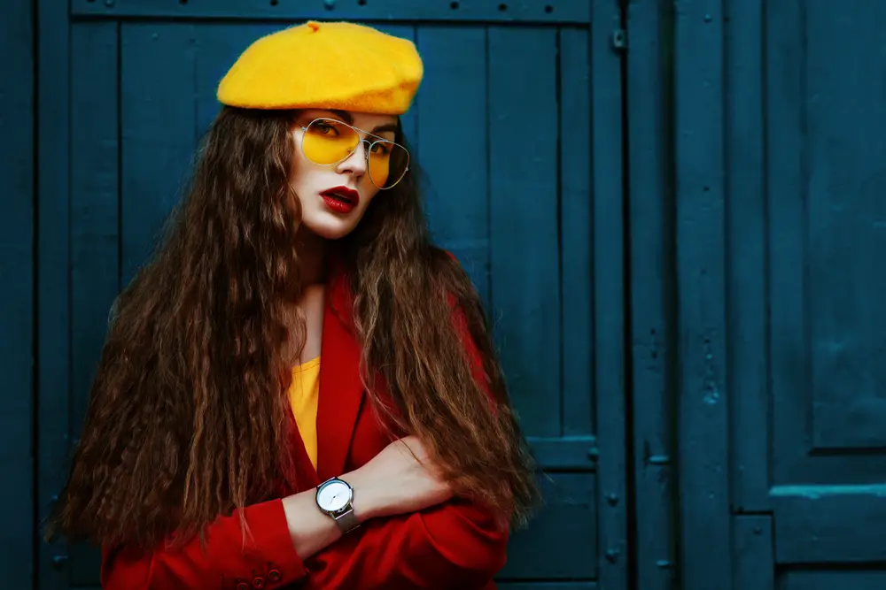 young beautiful fashionable woman wearing stylish yellow beret, trendy sunglasses, red blazer, wrist watch