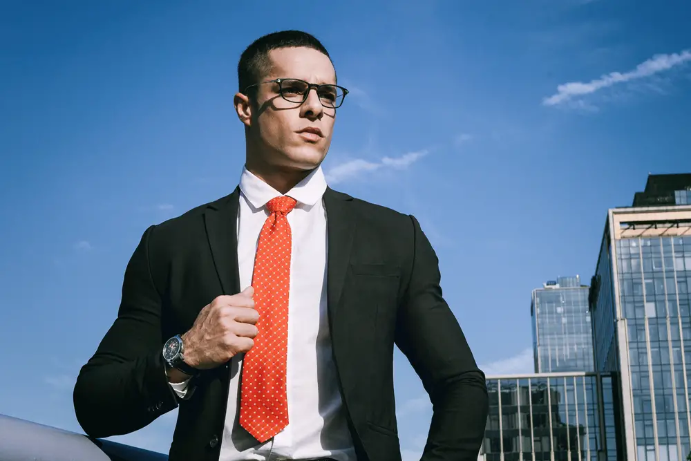 young fashion man wearing glasses, black suit and red tie